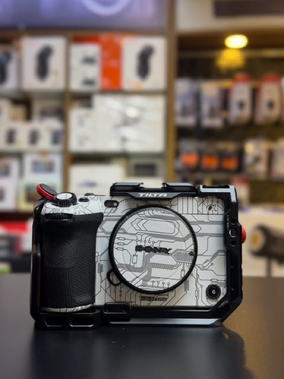 A caged mirrorless body on the counter, stock shelves behind